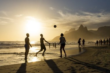 Sahilde futbol oynayan insanlar için Ipanema 'da güzel bir gün batımı manzarası, Rio de Janeiro, Brezilya