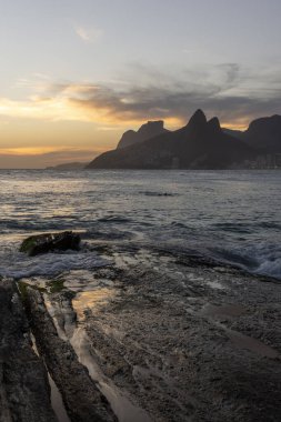 Ipanema Sahili, Rio de Janeiro, Brezilya 'da kayalara vuran dalgalara güzel bir gün batımı manzarası