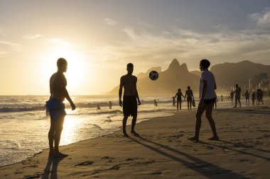 Sahilde futbol oynayan insanlar için Ipanema 'da güzel bir gün batımı manzarası, Rio de Janeiro, Brezilya