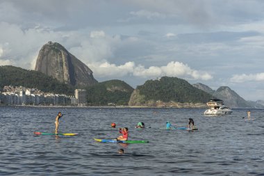 Copacabana Sahili 'ne güzel bir manzara. Arkasında Sugar Loaf dağı ve Stand Up Paddle tahtasındaki insanlar, Rio de Janeiro, Brezilya