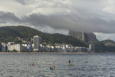Copacabana Sahili 'ne güzel bir manzara. Arkasında Sugar Loaf dağı ve Stand Up Paddle tahtasındaki insanlar, Rio de Janeiro, Brezilya