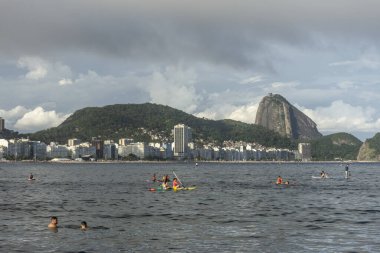 Copacabana Sahili 'ne güzel bir manzara. Arkasında Sugar Loaf dağı ve Stand Up Paddle tahtasındaki insanlar, Rio de Janeiro, Brezilya