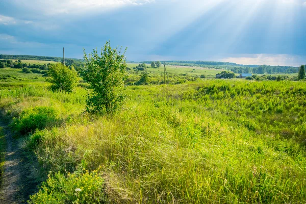 Güneş ışınları, fırtına gökyüzü altında bir vadi