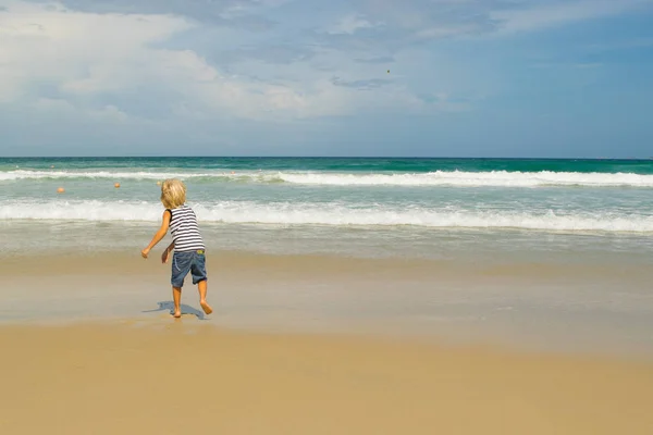 Ein blonder Junge (Kind), der eine Münze ins Wasser wirft, an der Küste (Strand), nha trang, Vietnam — Stockfoto