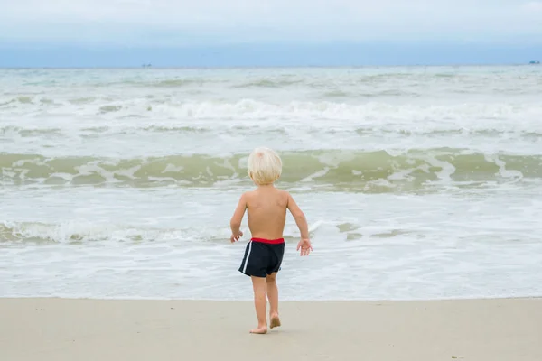 A thoughtful blond boy (child) staying near water at a sea shore (beach), Nha Trang, Vietnam — Stock Photo, Image