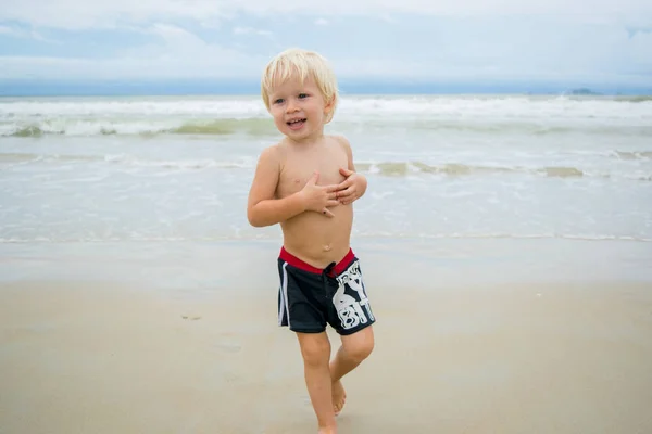 Ein nachdenklicher blonder Junge (Kind), der im Wasser an einer Meeresküste (Strand) spaziert, nha trang, Vietnam — Stockfoto