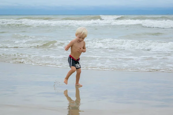 A thoughtful blond boy (child) walking in water at a sea shore (beach), Nha Trang, Vietnam — Stock Photo, Image