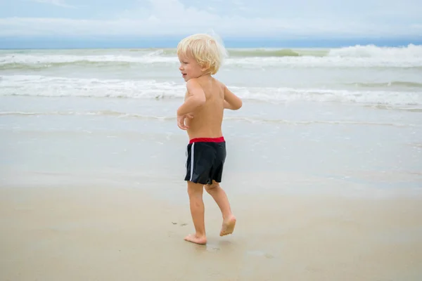 เด็กชายผมบลอนด์ที่คิดดี (เด็ก) เดินในน้ําที่ชายฝั่งทะเล (ชายหาด) นาตรัง, เวียดนาม — ภาพถ่ายสต็อก
