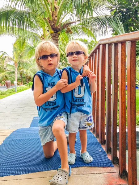 Two brothers in similar sunglasses and clothes at a tropical resort, Vietnam — Stock Photo, Image