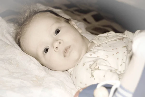 Un retrato facial de un niño en una cama mirando con interés — Foto de Stock