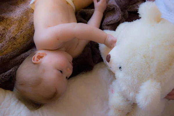 Un bebé curioso con un oso blanco de juguete — Foto de Stock