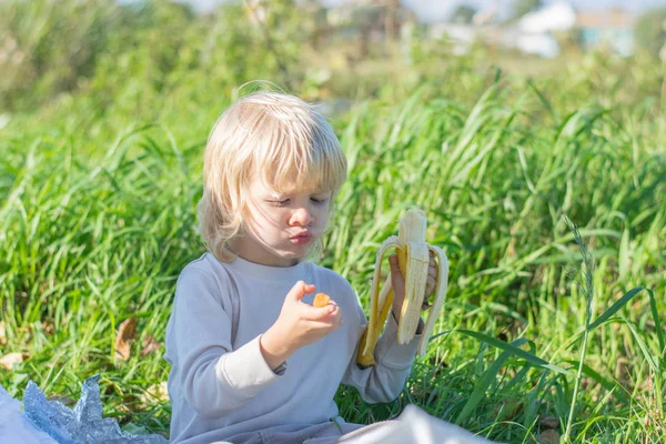 Blond chłopiec dziecko słowiańskich zjada marchewkę i banan — Zdjęcie stockowe
