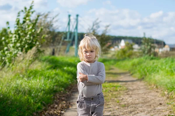 Ernstige blonde jongen verblijft omarmd zelf met zijn armen — Stockfoto