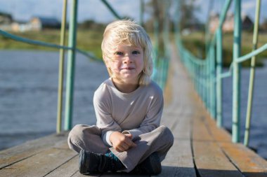 Eski bir ahşap kolye köprüde kalan mutlu sarışın çocuk