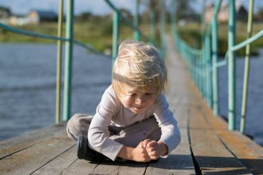 Eski bir ahşap kolye köprüde kalan mutlu sarışın çocuk