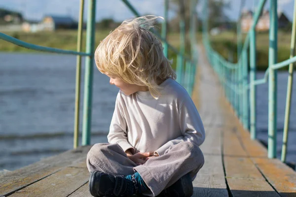 Eski bir ahşap kolye köprüde kalan mutlu sarışın çocuk