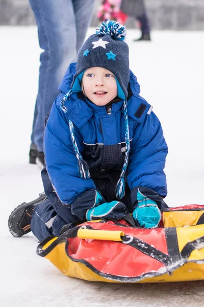 Happy boy toboggan from a snow slide on colorful tube — Stock Photo, Image