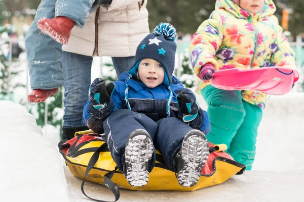 Happy boy toboggan from a snow slide on colorful tube — Stock Photo, Image