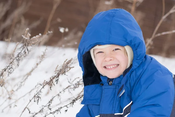 Niño feliz yaciendo en una nieve — Foto de Stock