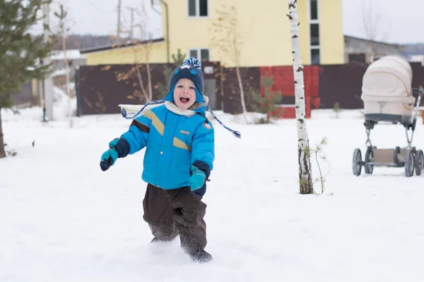 Happy boy running at a winter cottage village — Stock Photo, Image