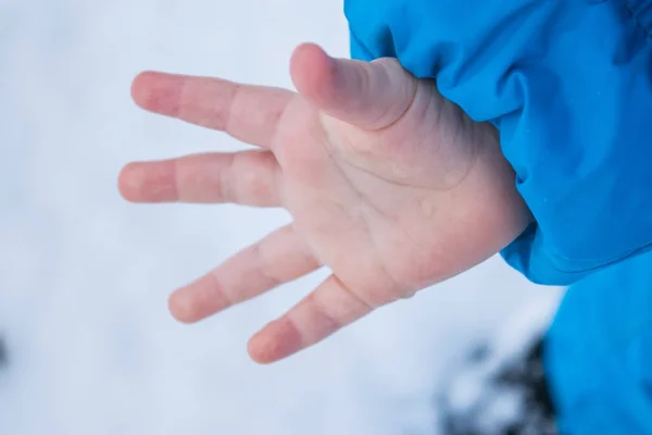 Una pequeña mano de un bebé en un fondo de nieve de invierno —  Fotos de Stock