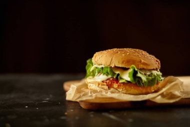 Siyah ahşap masadaki malzemeli hamburger.