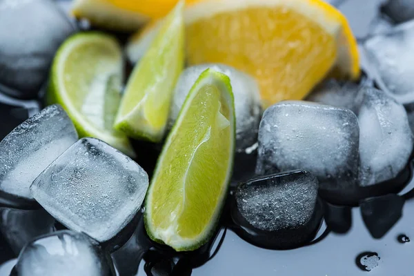 Fresh cutting fruits. Lime, orange, pomegranate with ice on the black wooden table