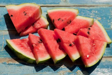 Mavi bir ahşap arka planda karpuz dilimleri.