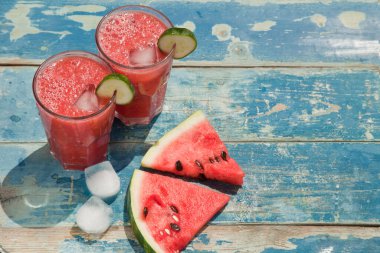 Mavi bir ahşap arka planda karpuz dilimleri.