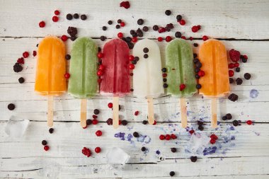 Çubukta dondurma, açık ahşap masada meyve.