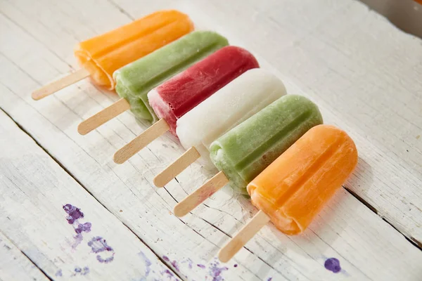 Ice cream on a stick with fruit on a light wooden table