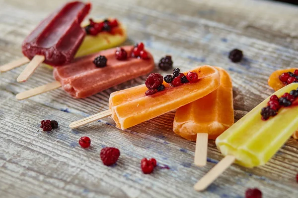 Ice cream on a stick  with fruit on the wooden table