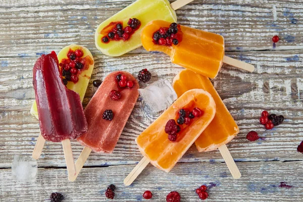 Ice cream on a stick  with fruit on the wooden table