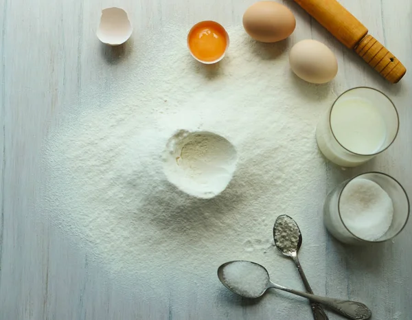 Eier, Mehl, Milch, Zucker auf einem weißen Holztisch. — Stockfoto
