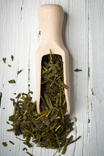 Grüne Teeblätter mit Schaufel auf Holzgrund — Stockfoto