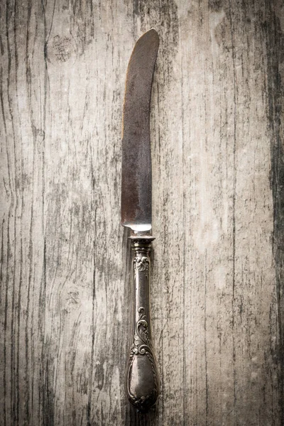 Old knife on wooden background.