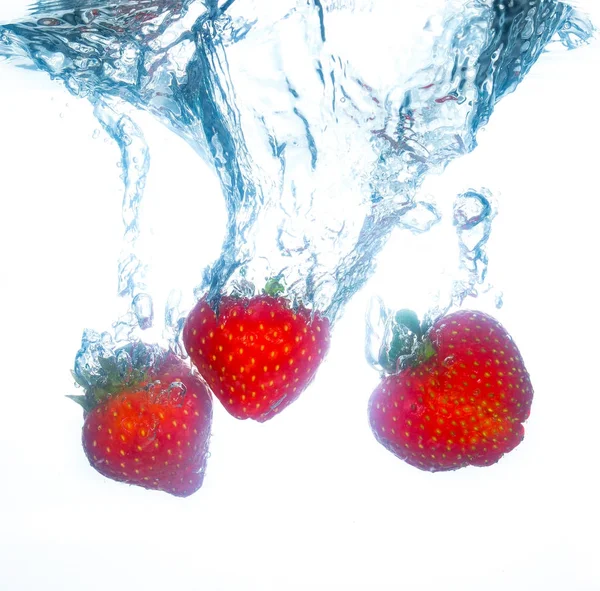 Fraises tombant dans l'eau et éclaboussures — Photo