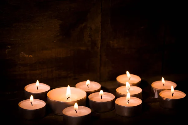 Tealight candles on dark wooden background — Stock Photo, Image