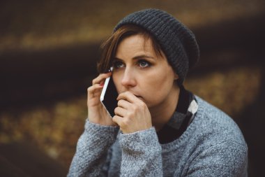Ormanda smartphone ile tek başına oturan üzgün kadın portresi. Yalnızlık kavramı. Millenial sorunları ve duyguları ile ilgili.
