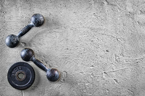 Fitness or bodybuilding background. Old iron dumbbells on conrete floor in the gym. Photograph taken from above, top view — Stock Photo, Image