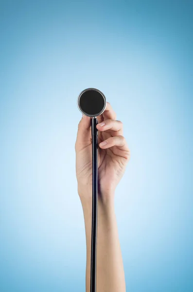 Mano femenina sosteniendo un estetoscopio aislado sobre fondo azul — Foto de Stock