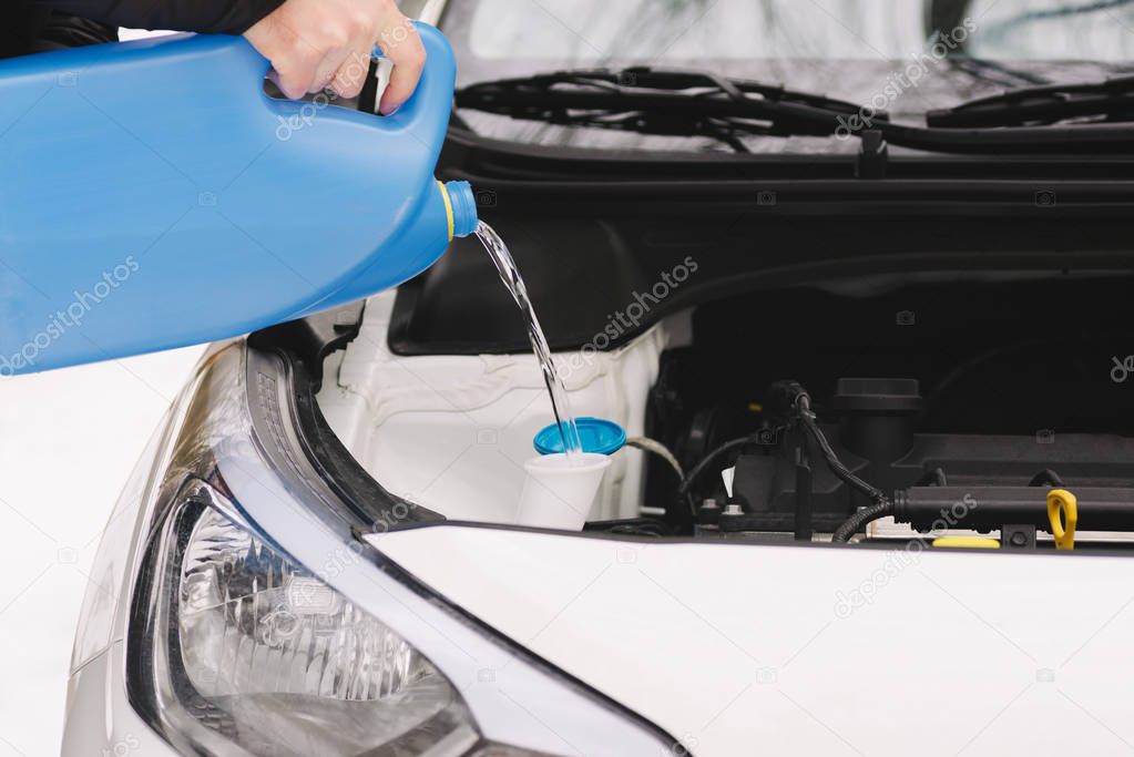 Man pouring car winter windshield washer fluid