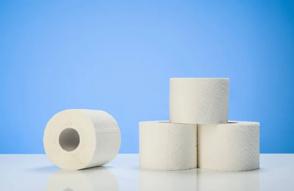 Toilettenpapier isoliert auf weißem Tisch mit blauem Hintergrund — Stockfoto
