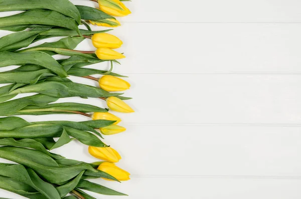 Фон с желтыми тюльпанами, на белом деревянном столе — стоковое фото