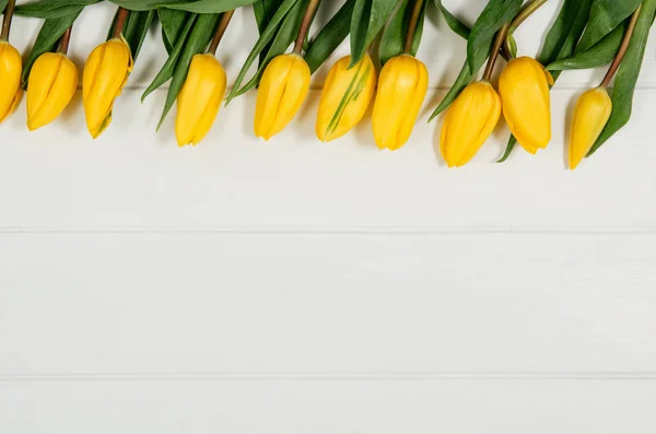 Hintergrundrahmen mit gelben Tulpen, auf weißem Holztisch — Stockfoto