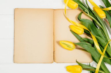 Arka plan beyaz tahta masada boş Not Defteri ile Sarı laleler,