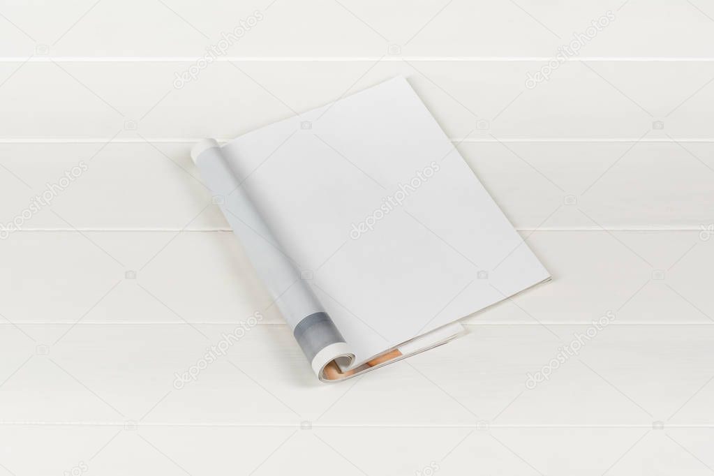 Mock-up magazines or catalog on white wooden table background.