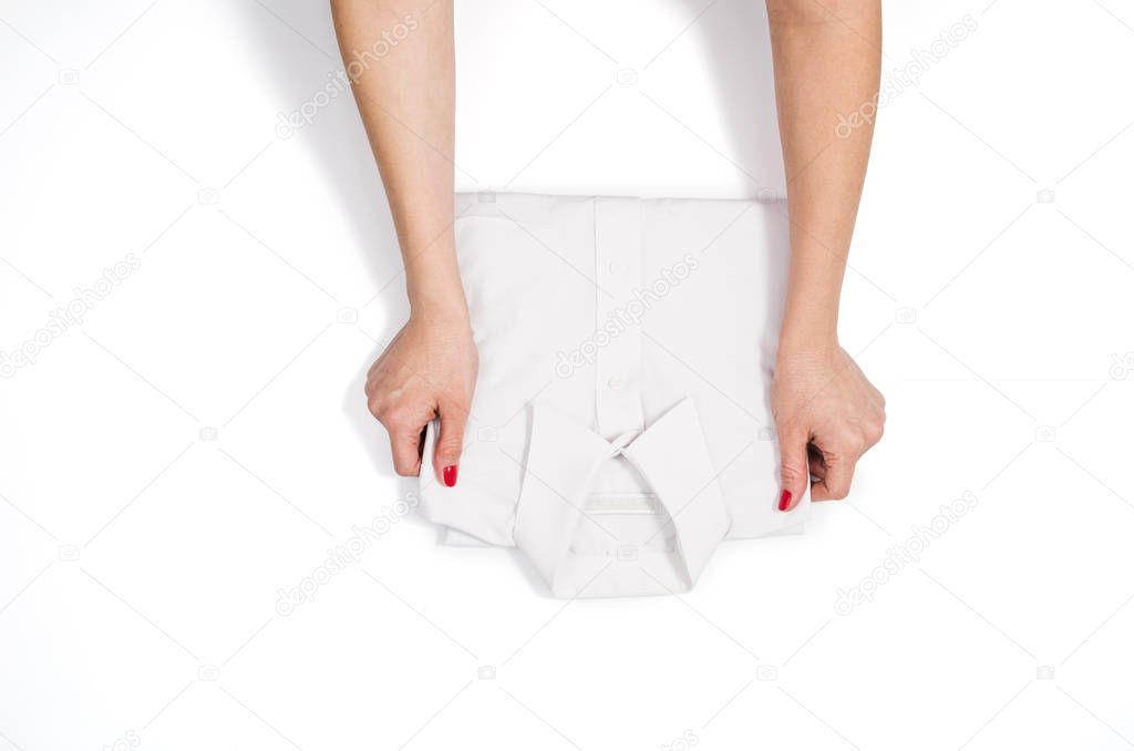 Woman folding clothes. Top view on white background with copyspace