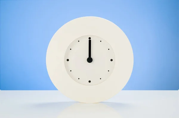 Relógio branco na mesa branca com fundo azul sem costura — Fotografia de Stock