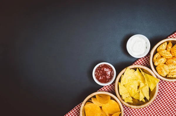 Burgonya chips és snackeket, fekete pala asztalon, felülnézet — Stock Fotó